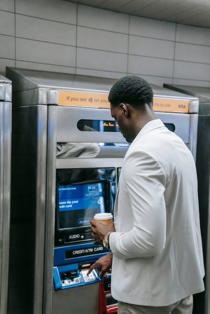 Businessman with coffee uses ATM indoors. Finance and transactions made simple.